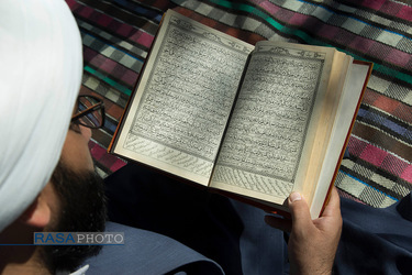 در ایوان منزل مشغول مطالعه قرآن است